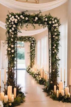 an aisle decorated with greenery, candles and white flowers for a wedding or reception