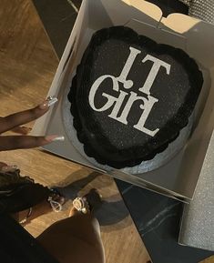 a cake in a box with the words it girl on it and someone's hand