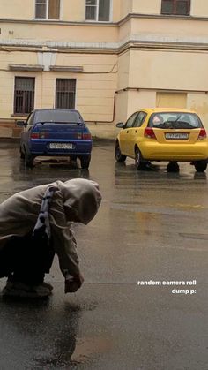 a person kneeling down in the middle of a parking lot with cars parked behind them