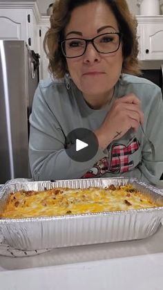 a woman sitting in front of a pan of food