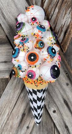 an ice cream cone decorated with eyeballs and sprinkles is hanging from a wooden fence