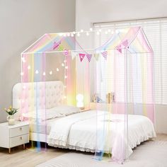 a white bed sitting in a bedroom next to a window with curtains on top of it