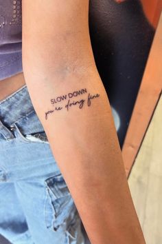 a woman with a tattoo on her arm that says slow down from the very far end