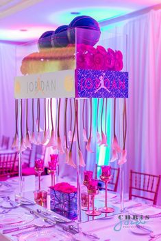 a table topped with lots of pink and purple flowers next to tall vases filled with candles