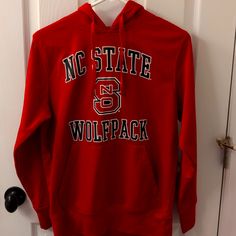 a red sweatshirt with the nc state wolfpack on it hanging from a white door