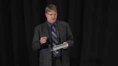 a man standing in front of a black curtain holding a book