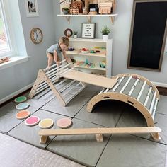 a child playing with a wooden bed frame and paint samples on the floor in front of it