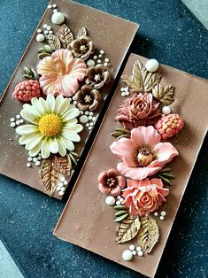 two pieces of paper with flowers on them sitting on top of a blue countertop