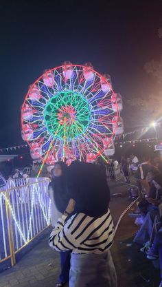 a woman taking a photo of a ferris wheel at night