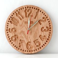 a wooden clock with numbers on the face and hands is shown in front of a white wall