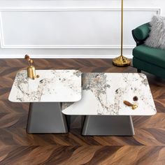 two tables with marble top sitting on a wooden floor in front of a green chair