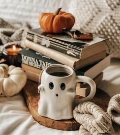 a coffee mug sitting on top of a wooden tray next to books and pumpkins