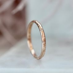 a gold wedding band with small stars on the inside and outside, sitting on a white surface