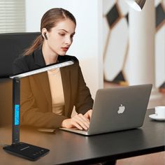 a woman sitting in front of a laptop computer on top of a desk with headphones