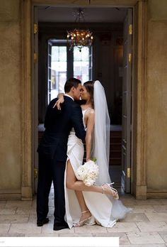 a bride and groom kissing in front of an entrance