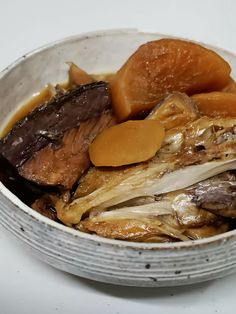 a bowl filled with meat and vegetables on top of a white countertop next to a knife