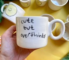 a hand holding a coffee mug with the words cute but overthik written on it