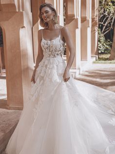 a woman in a white wedding dress standing on the sidewalk with an archway behind her