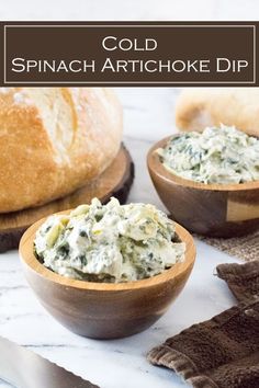 two wooden bowls filled with spinach artichoke dip on top of a marble counter