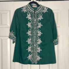 Prettiest shade of emerald green tunic embroidered around the neckline, front and sleeves. With pretty white pearlescent buttons down the front. A great addition to your wardrobe for summer.  Made to fit a bit loose. Made of 100% cotton. Fits a size M or L best.  Brand:  Shoje  Made in the Phillipines Green Embroidered Long Sleeve Tops, Green Long Sleeve Blouse With Resham Embroidery, Green Long Sleeve Tops With Resham Embroidery, Green Tops With Resham Embroidery For Spring, Green Resham Embroidered Top For Spring, Green Embroidered Shirt For Spring, Spring Green Embroidered Shirt, Green Long Sleeve Embroidered Top, Spring Embroidered Green Blouse