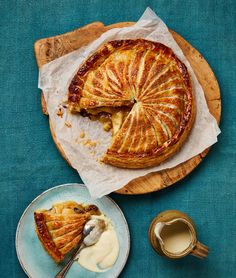 a pie on a wooden plate next to a bowl of yogurt and a fork