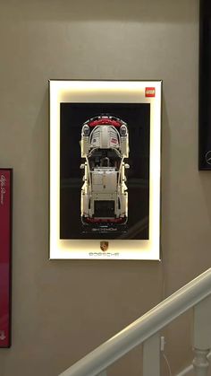 a framed photograph of a car on the wall next to a stair case in a building