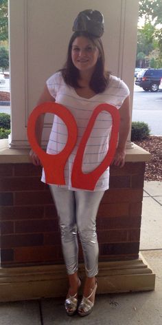 a woman in white shirt and silver pants holding up a sign