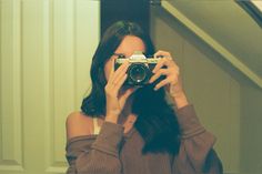 a woman taking a selfie in front of a mirror with her camera up to her face