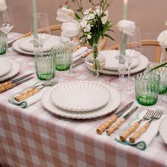 the table is set with plates, silverware and flowers