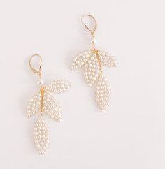 two pairs of earrings with pearls hanging from the ends and leaves on each earring