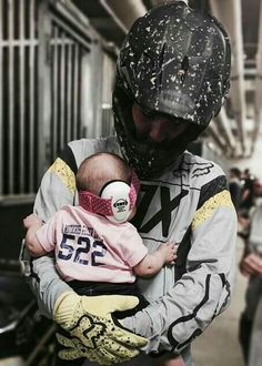 a man holding a baby wearing a helmet