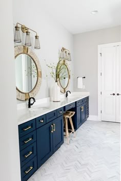 a bathroom with blue cabinets and mirrors on the wall, along with two stools