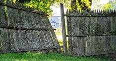 an old wooden fence with moss growing on it and grass in the yard behind it