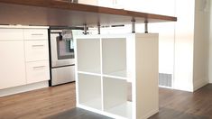 an empty kitchen with white cabinets and wood floors