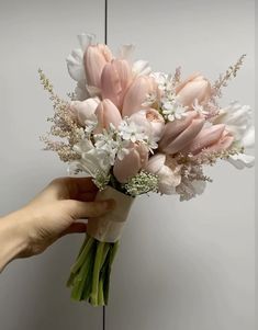 a hand holding a bouquet of flowers in front of a mirror with white and pink flowers