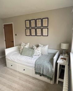 a white bed sitting in a bedroom next to a wall with pictures on the wall