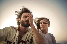 a man and woman sitting next to each other with their hair blowing in the wind