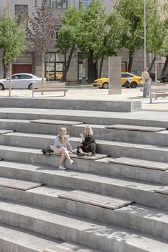 two women sitting on steps in front of a building