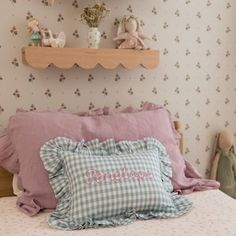 a bed with pillows and stuffed animals on the headboard next to a shelf above it