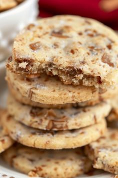 a stack of cookies sitting on top of a white plate next to a bowl of nuts