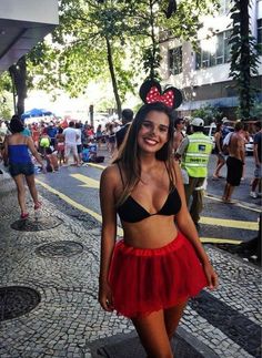 a woman in minnie mouse ears and red skirt posing for a photo on the street