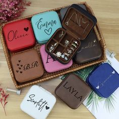 six personalized jewelry cases sitting on top of a wooden table next to some flowers