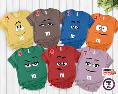 six different colored shirts with faces and numbers on them, all showing the same face