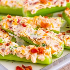 several green peppers topped with cheese and bacon on a white platter next to glasses