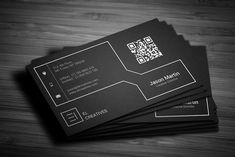 three black business cards with qr code on the front and bottom, sitting on a wooden table