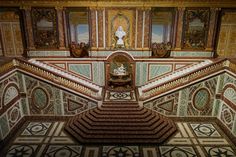 an elaborately decorated room with stairs and paintings on the walls