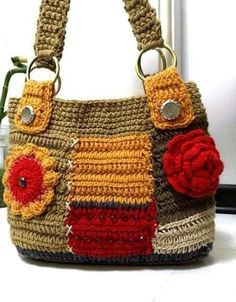 a crocheted handbag with flowers on the front and side, hanging from a hook