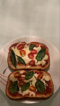 two pieces of bread with cheese and vegetables on them are sitting on a white plate