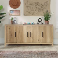 a living room with a rug, wooden cabinet and potted plants on the wall