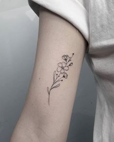 a woman's arm with a small flower tattoo on the left side of her arm